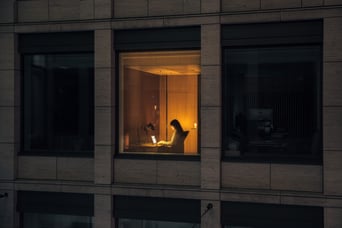 Person sitting in a lit window.