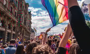 People marching for Pride, waving a Pride flag 